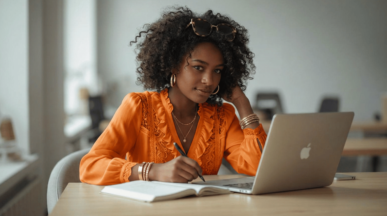 Mulher jovem negra em café com caderno aberto e laptop, escrevendo com foco — segredo da motivação nos estudos
